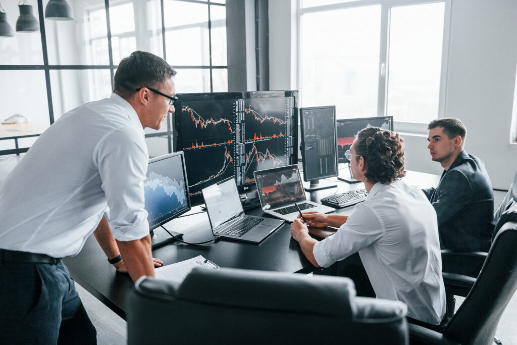 Conception of teamwork. Team of stockbrokers works in modern office with many display screens